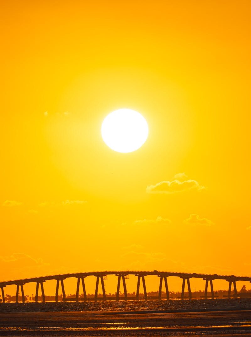 A breathtaking Florida sunset casting a golden glow over a scenic bridge and calm waters.